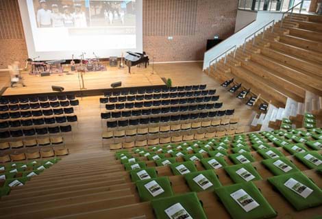 Fold ud stol i grøn filt i auditorium