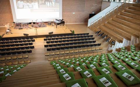 Fold ud stol i grøn filt i auditorium