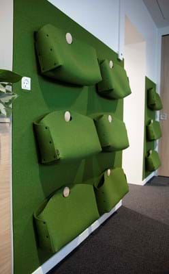 Kontortasker i grøn filt ophængt på væg med filt i samme farve