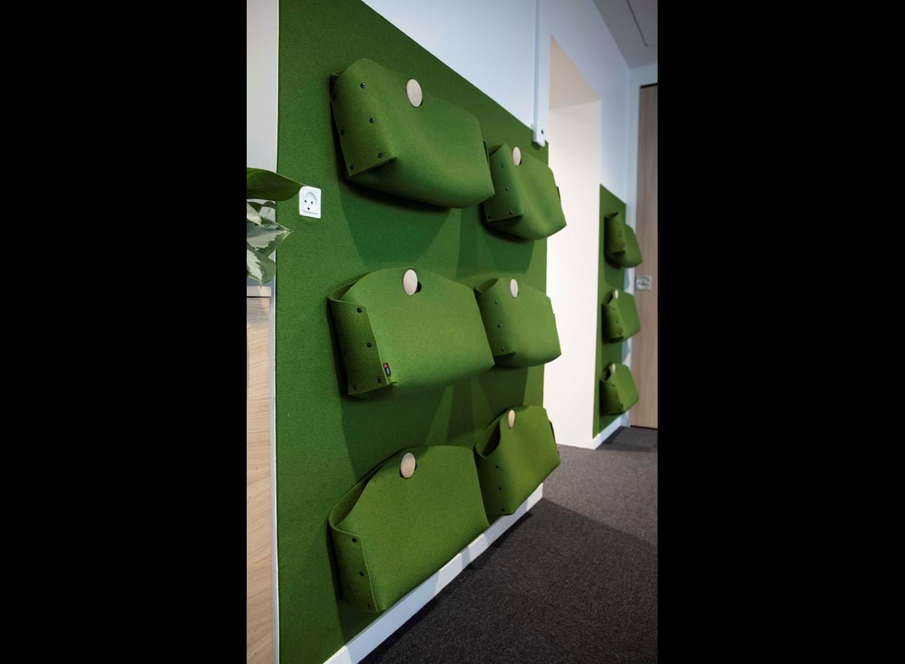 Kontortasker i grøn filt ophængt på væg med filt i samme farve