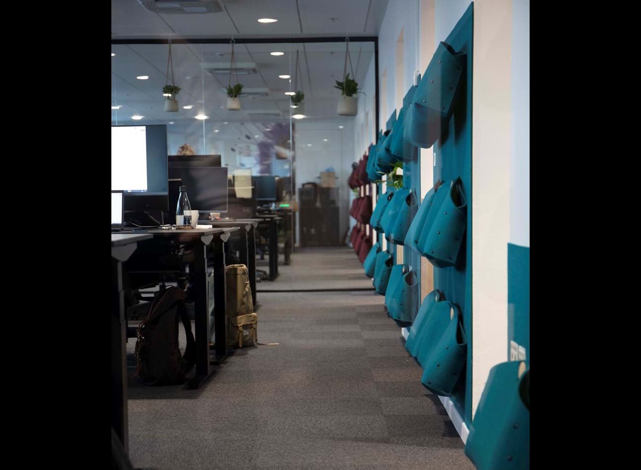 Kontortasker i blå filt ophængt på væg med filt i samme farve