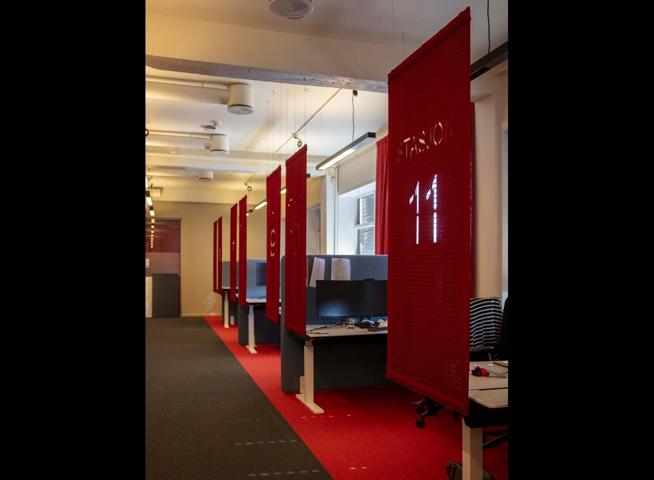 Cover i rød filt foran syv arbejdsstationer, YX stasjon, Norge